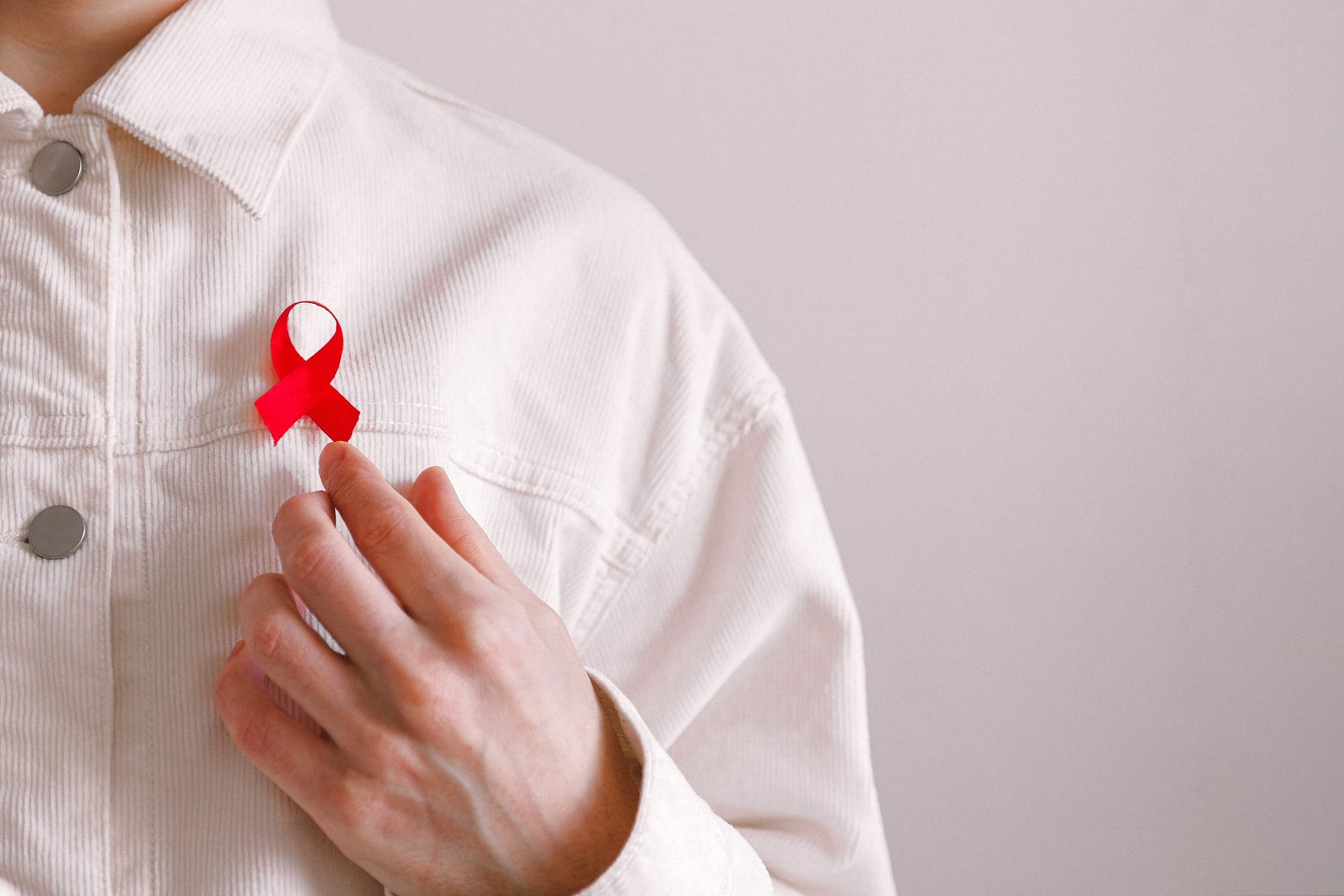 Homem com uma fita vermelha na camisa no Dia Mundial da SIDA