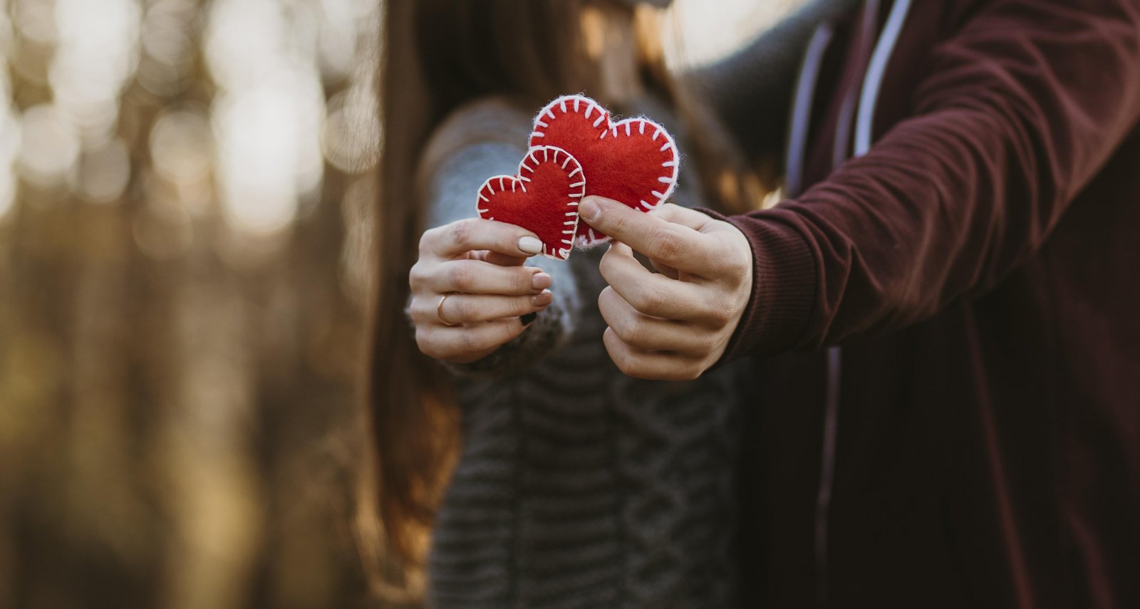 Um par de amantes segura dois corações vermelhos nas mãos para o Dia dos Namorados