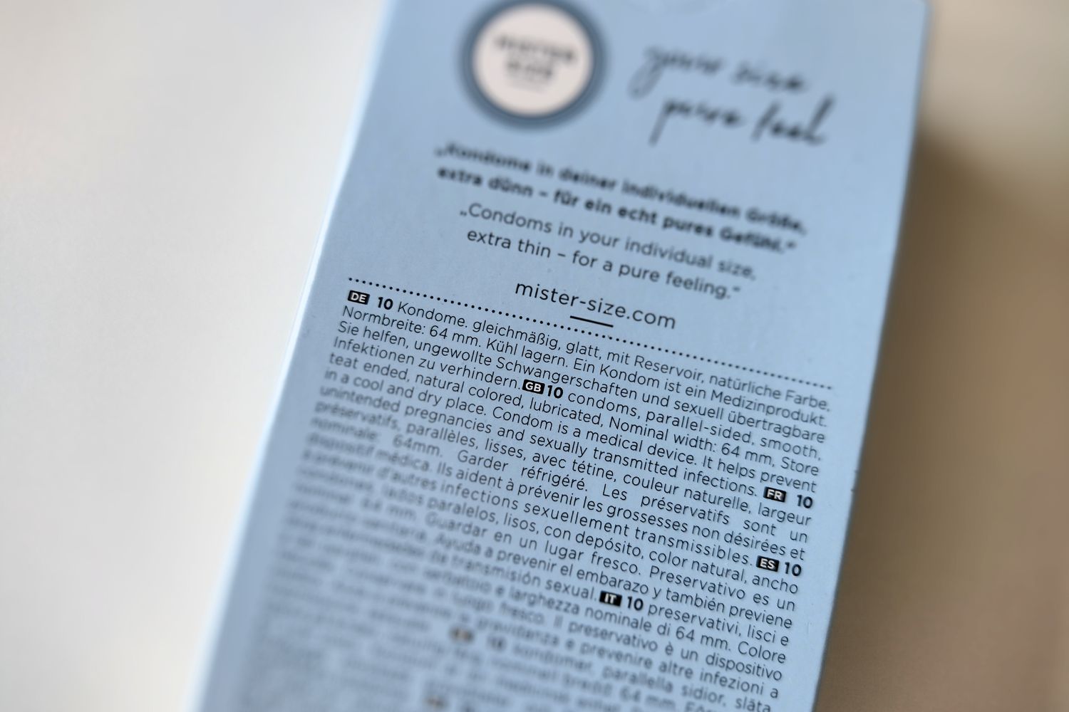 Embalagem de preservativos com indicação da largura normalizada no texto